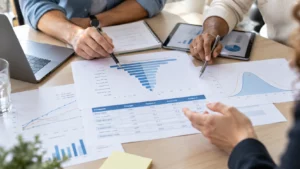 Professionals reviewing sensitivity analysis charts, including a tornado diagram and probability distributions, to identify key factors influencing model outcomes.
